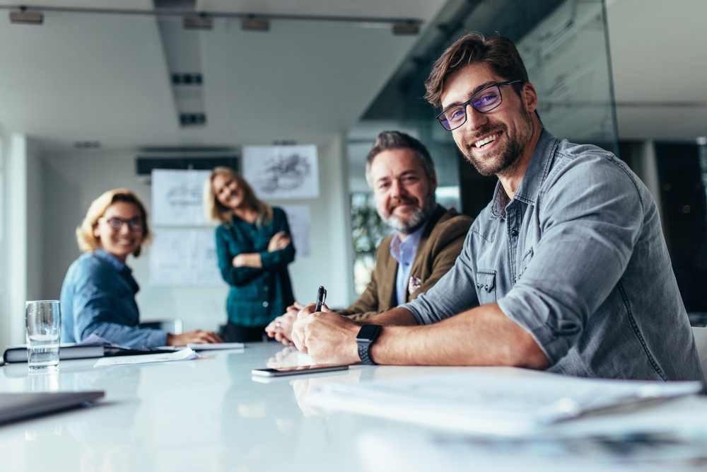 Happy,Group,Of,Businesspeople,During,Presentation.,Colleagues,Looking,At,Camera