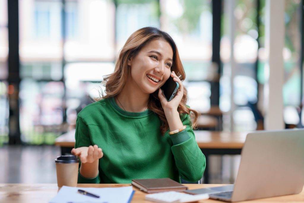 Asian businesswoman sitting with her laptop happily chatting on
