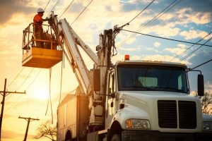 Andesco 2025. Trabajador de utility realiza mantenimiento eléctrico con camión grúa, representando la operación confiable y digitalización en servicios públicos en América Latina
